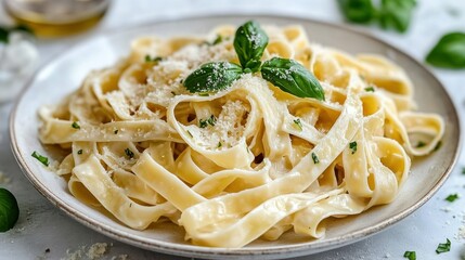 Creamy fettuccine pasta dish with parmesan cheese and basil.  Freshly cooked fettuccine pasta tossed in a light, creamy sauce.  Garnished with grated parmesan cheese and fresh basil leaves