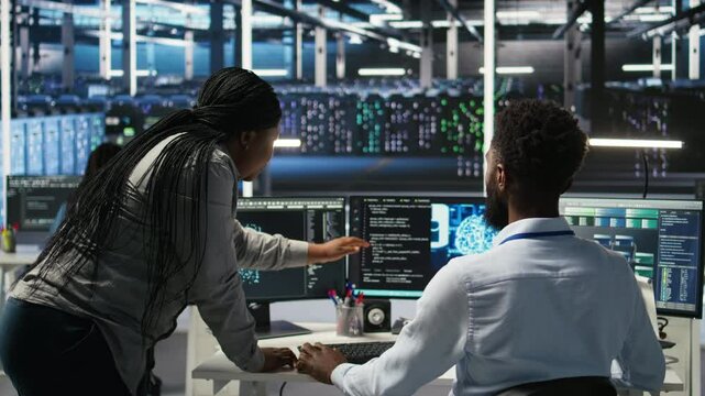 Manager supervising data center engineer using AI neural network models to configure hardware. Team leader overseeing employee using machine learning programming language to optimize systems, camera A