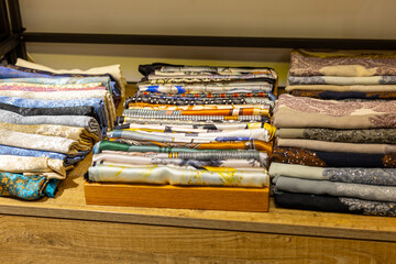 Colorful fabrics neatly stacked in a textile store showcasing a variety of textures and patterns...