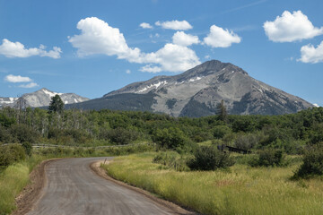 Scenic mountain view along a winding dirt road on a sunny day in the countryside