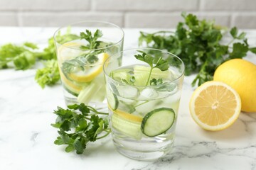 Healthy drink with parsley, cucumbers, lemons and celery on white marble table, closeup