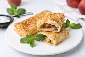 Tasty apple strudels and mint on white table, closeup
