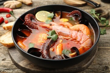 Delicious seafood soup in bowl on wooden table, closeup