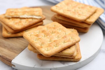 Tasty salty crackers on white table, closeup