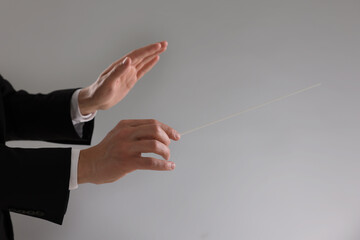 Conductor with baton on grey background, closeup