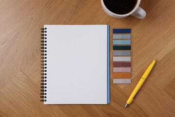 Open blank notebook, coffee, bookmarks and pen on wooden table, flat lay