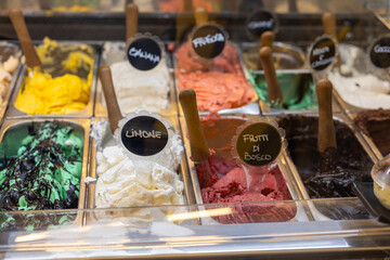 Colorful gelato selection displayed in a local dessert shop during summer in an urban area