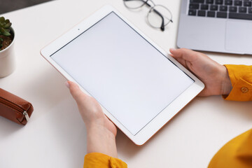 Woman with tablet at white desk indoors, closeup