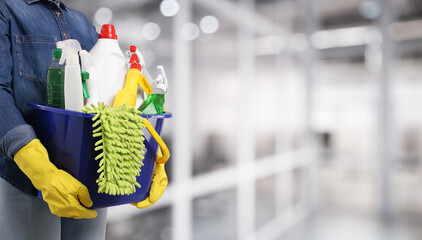 Woman with different cleaning supplies and products in office, closeup. Banner design with space...