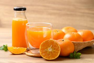 Orange juice in glass and bottle with fresh orange fruit in basket on wooden background, Healthy drink