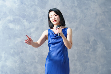 マイクを持って歌う青いドレスを着た女性シンガー