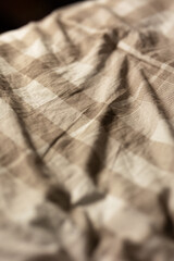 close-up of a soft slept-in comforter that is beige and checkered in soft moody lighting, image of a cozy blanket
