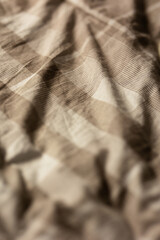 close-up of a soft slept-in comforter that is beige and checkered in soft moody lighting, image of a cozy blanket
