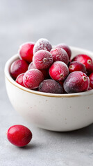Frosted cranberries in ceramic bowl on gray background macro