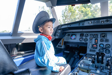 Boy child at controls of airplane sitting in cockpit wearing a pilot hat and sitting in an airplane cockpit, smiling confidently, portraying dreams of aviation and the future of flight.