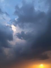 Dramatic sky with dark storm clouds and a bright golden glow on the horizon, creating a contrasting and powerful visual effect.