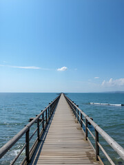 Obraz premium A long pier stretching out into the ocean with calm waters and sunny sky