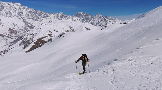 Man Climb To The Snowy Peak Of Caucasian Mountain With Skis. - aerial shot