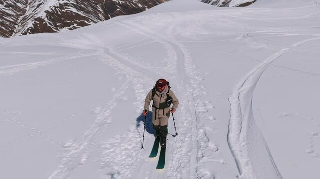 Lone Man Climbing On Top Of The Caucasian Mountains Covered With Snow In Georgia. - aerial shot