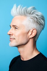 Fototapeta premium A stylish male making a statement. Elegant men's short rebellious haircut - midlife white man with white hair. Design idea design of style for aging men. Blue solid background.