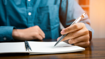 Male hand taking notes on the notepad. businessman working at work table, checklist writing planning investigate enthusiastic concept. focus on man hand holding pen, putting signature at official pape