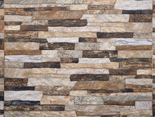 Irregular stone wall texture background in warm earth tones. Rough beige, tan, brown, gray, black stones surface. Uneven staggered pattern, natural rustic aesthetic, durability, nature, timelessnes. 