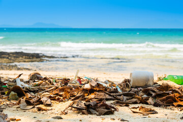 Plastic waste, plastic cups at the beach. Concept of environmental problems and saving the plane	
