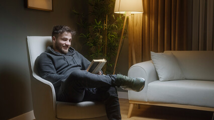 A man is sitting in a chair reading a book