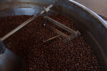 Photo of coffee beans roasting in a large metal drum - a blend of Arabica and Robusta for producing premium coffee with excellent taste.	