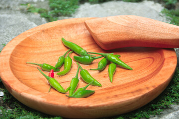 cayenne pepper on a wooden mortar with a grass background