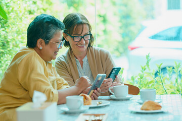 Elderly woman wearing glasses using a phone with friends 