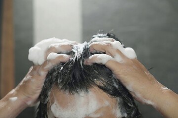 Naklejka premium man bathing wash his hair with shampoo in shower. for hygiene. Liquid drops, and foam wash for texture and cleaning routine.