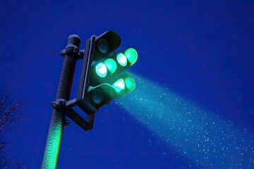 Frosty green traffic light at night, glowing beam