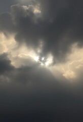 Obraz premium plane flying through a cloudy sky with the sun peeking through the clouds
