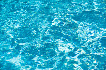 Blue pool water background. Blurred transparent clear calm water surface texture. Water waves in sunlight with copy space.