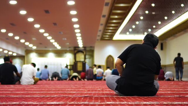 A man enjoys some relaxing time with a blurred background of worshippers performing prayers