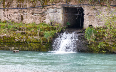 Obraz premium A small stream of water flows into a large hole in a rock