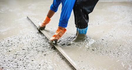 man in a blue shirt and orange boots is working on a concrete slab