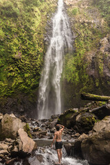 Adult man observing a background landscape with a waterfall of pure water in the middle of the mountain surrounded by tropical forest and Costa Rican jungle