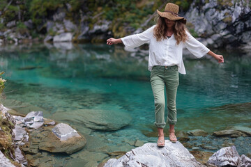 A photo of a woman in green pants and a white shirt, wearing a hat