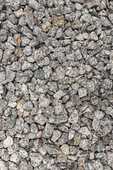 A close-up texture of crushed granite stones in various shades of gray and white, creating a rough and natural ground cover surface
