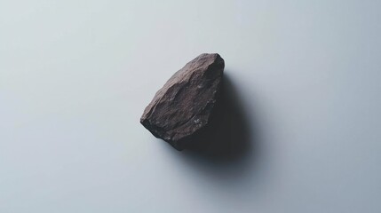 Naklejka premium Single textured stone casting a soft shadow against a seamless backdrop