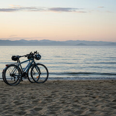 Obraz premium two bicycles parked on a sandy beach at sunset overlooking a calm ocean