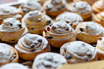 Close-up of freshly baked pastries topped with powdered sugar and raisins, emphasizing texture and...