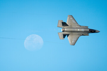 F35 flying in the sky passing the moon 