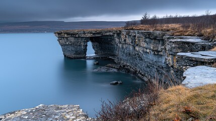 The natural stone archway stands over calm blue water landscape