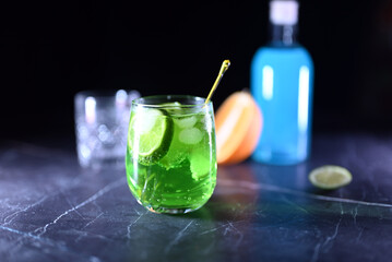 Mojito cocktail with lime wedges and ice on black background