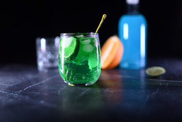 Mojito cocktail with lime wedges and ice on black background