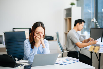 Fototapeta premium Young beautiful woman typing on tablet and laptop while sitting at the working white table