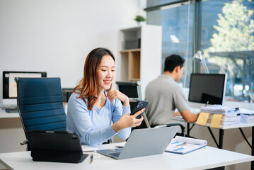 Young beautiful woman typing on tablet and laptop while sitting at the working white table